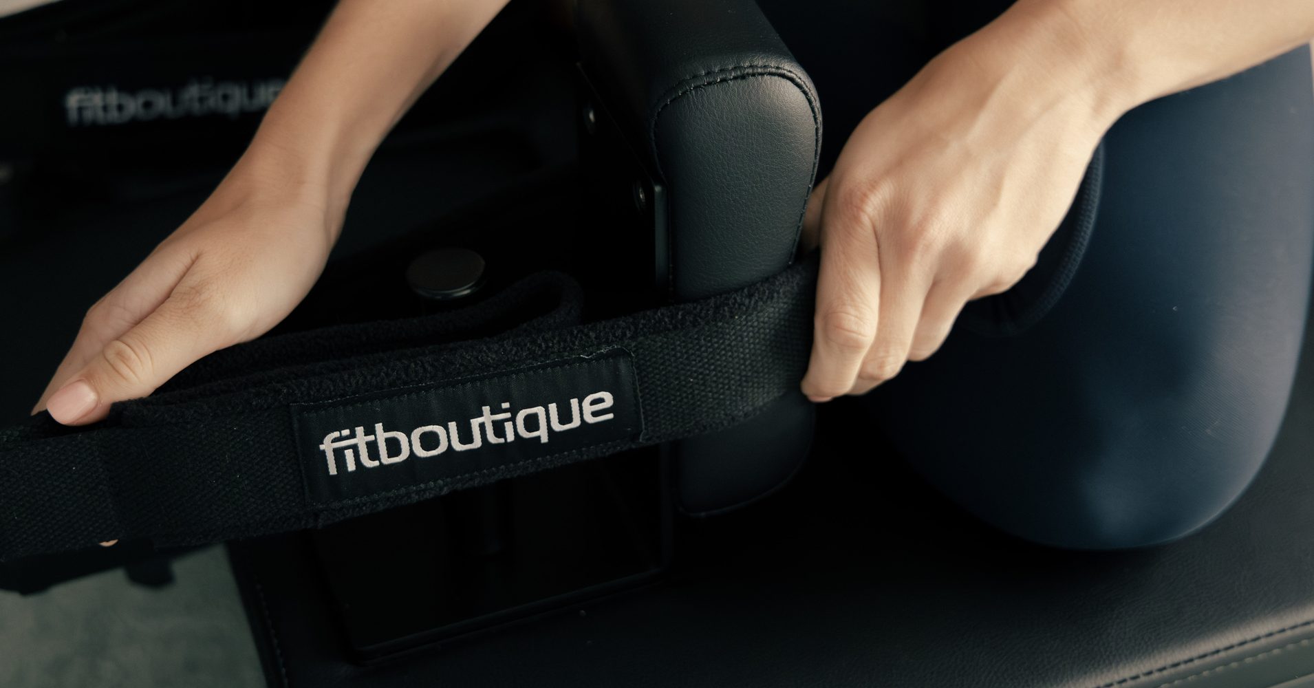 Hand gripping the strap on a FitBoutique reformer